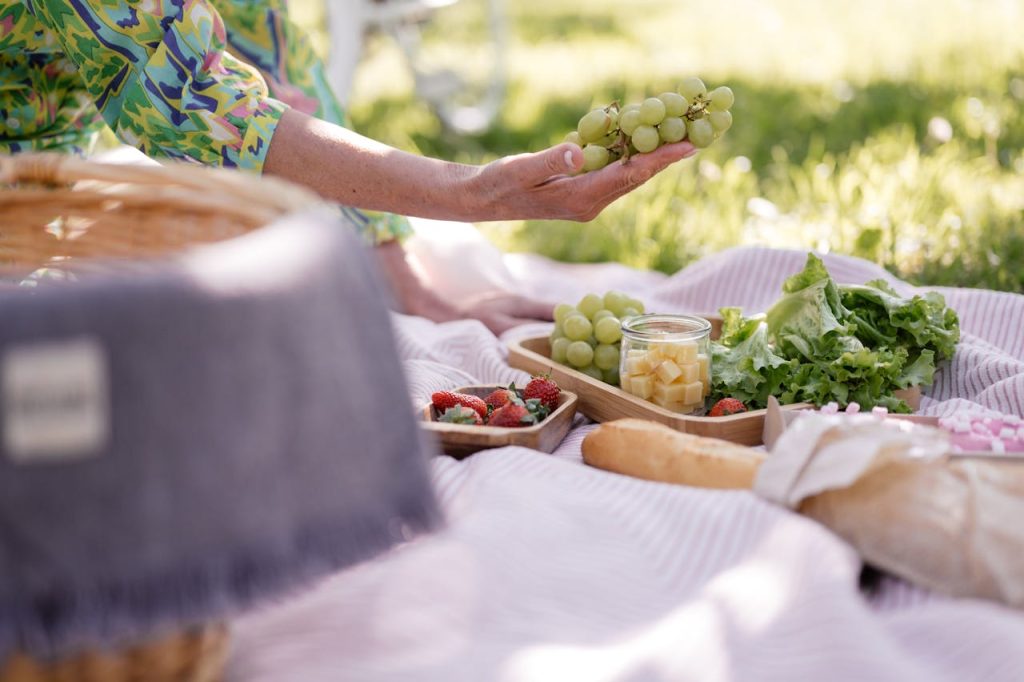 A vibrant picnic scene with fresh grapes, strawberries, and greens outdoors.